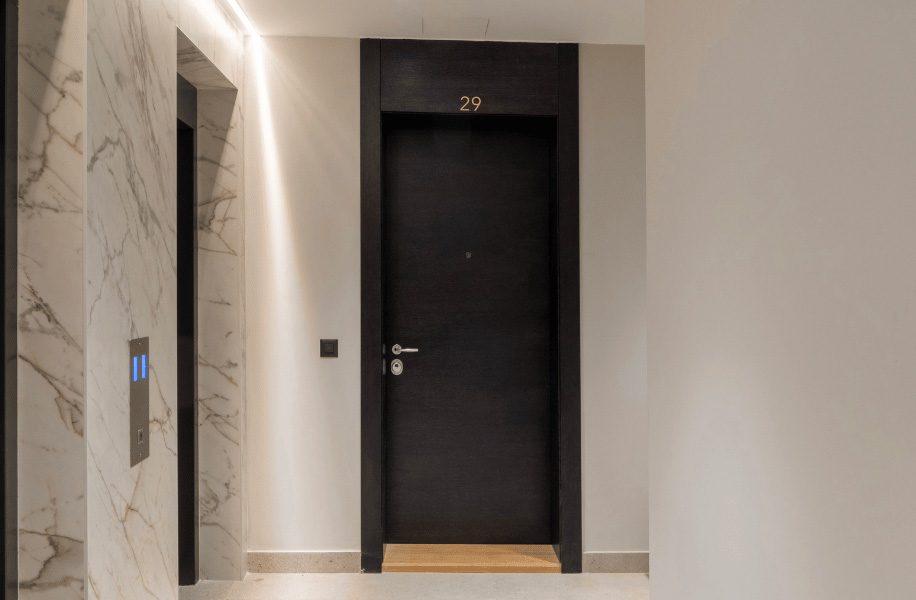 Porte d’entrée d’appartement en bois foncé avec cadre élégant et numéro 29 dans un hall moderne