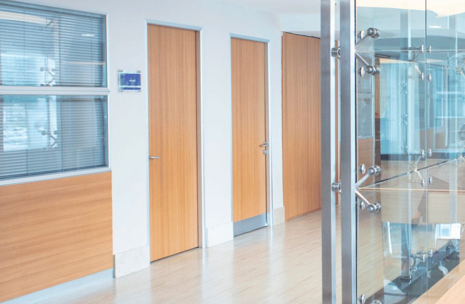 Portes en bois clair dans un couloir de bureau moderne avec cloisons vitrées