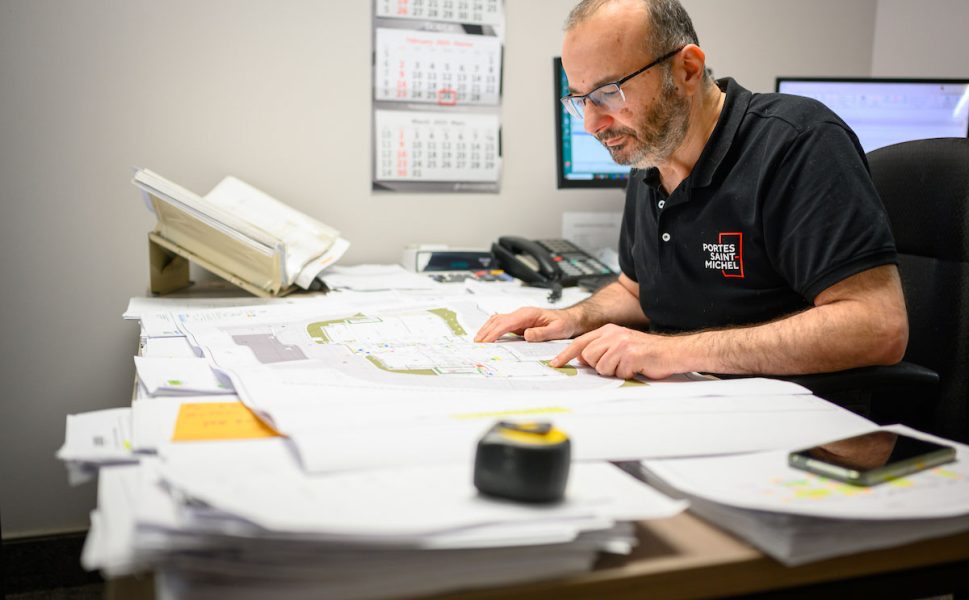 Chef de projet Portes Saint-Michel étudiant des plans techniques pour la fabrication de portes